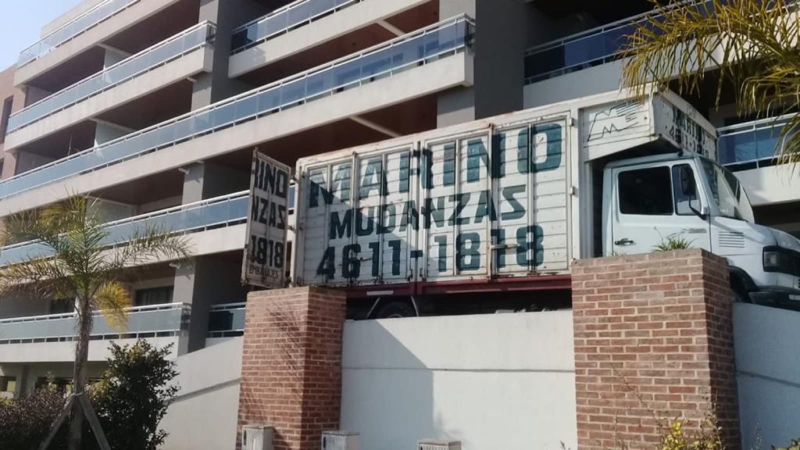 Camión de Marino Mudanzas estacionado frente a un edificio, visto desde abajo