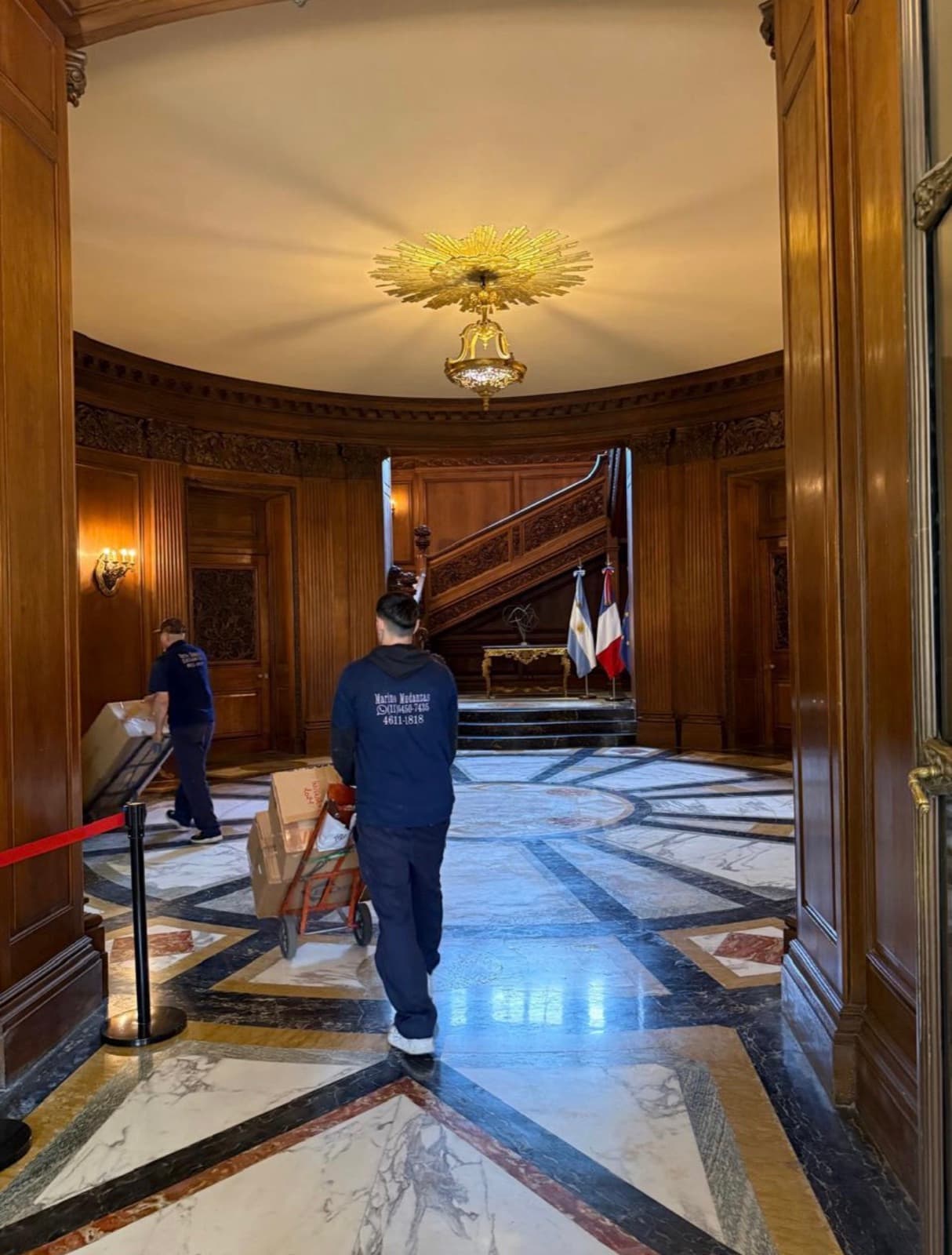 Operarios de Marino Mudanzas trasladando cajas por un hall de mármol y madera