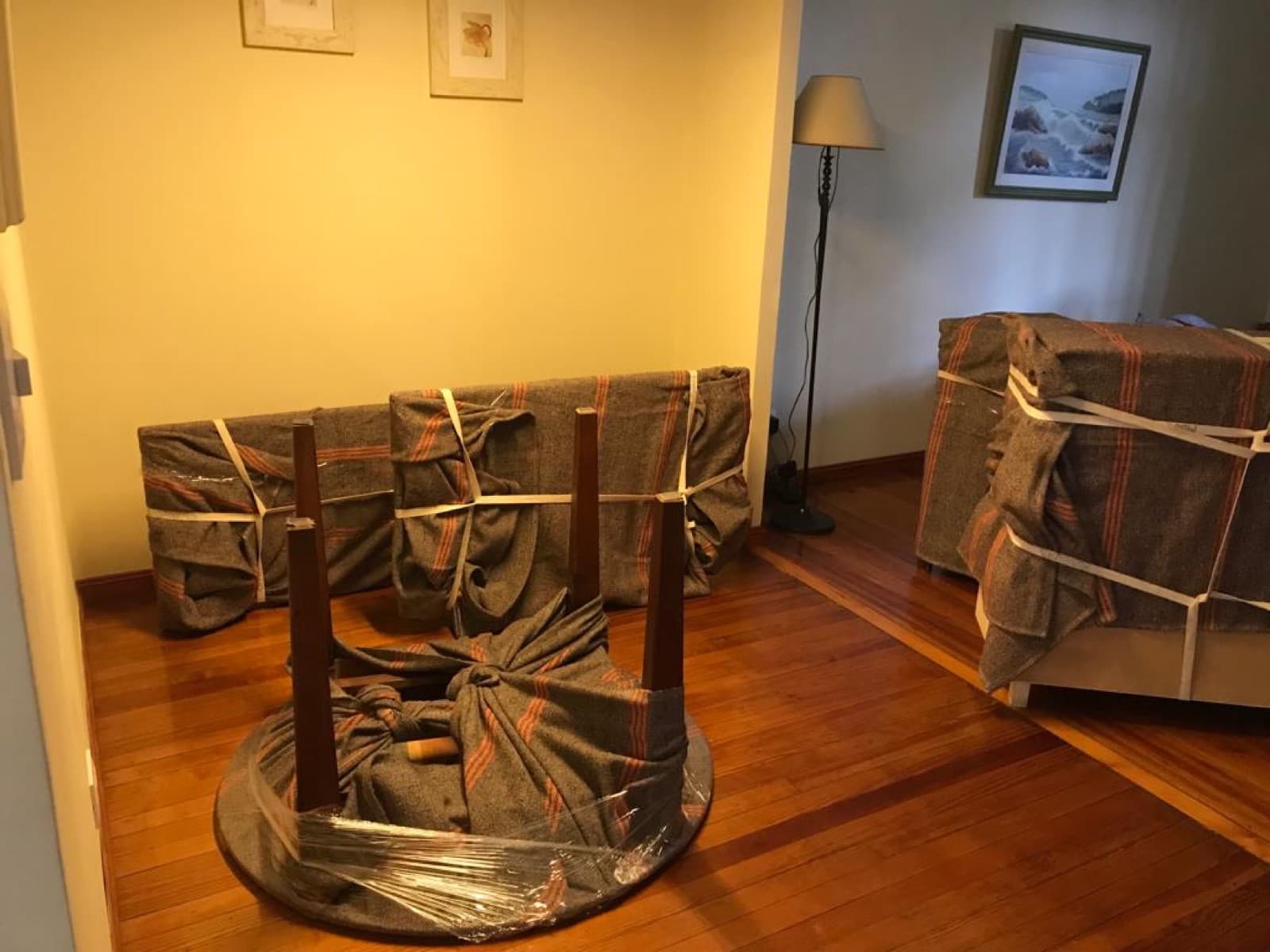 Mesa y muebles embalados con mantas en un living, listos para cargar