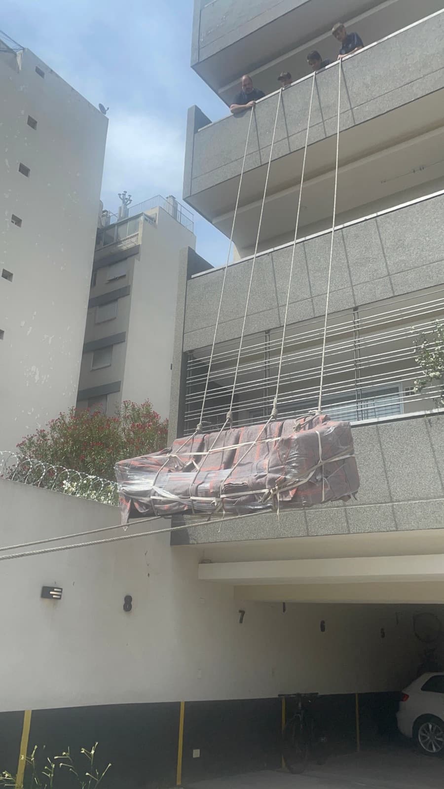 Sofá embalado bajando por soga desde un balcón